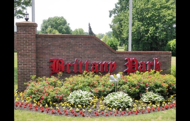 a brick wall with a red sign and flowers in front of it