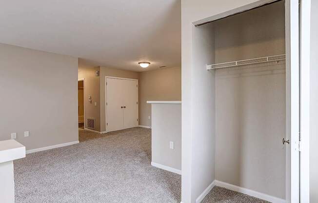 A white closet with a shelf and a white door.