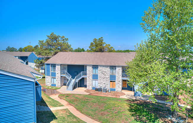 a blue house with a yard and trees in front of it