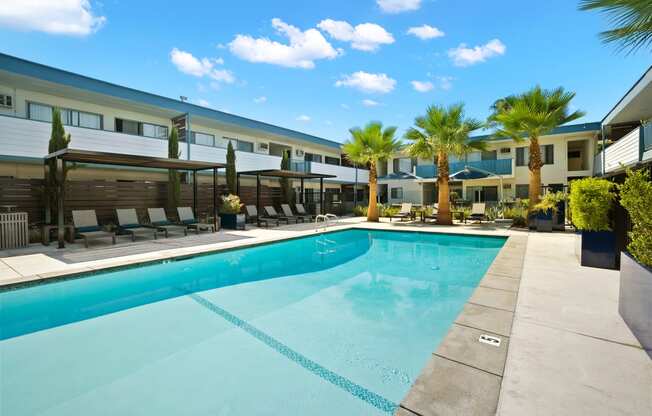 a swimming pool with palm trees and a building in the background