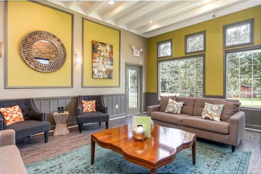 A living room with a grey couch, a brown coffee table, and a woven basket on the wall.