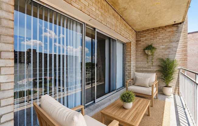 A balcony with a table and chairs overlooking a cityscape.