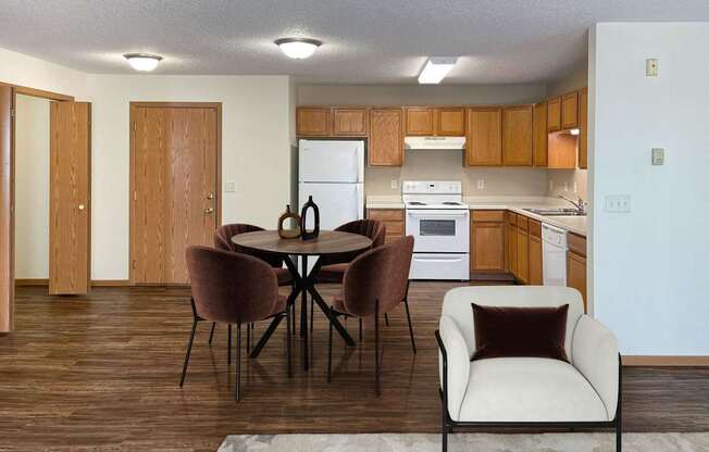 A kitchen with a table and chairs in the foreground. Bismarck, ND Sierra Ridge Apartments