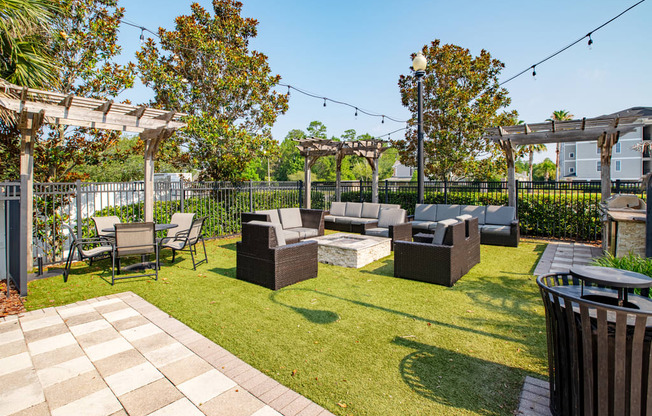 a grass patio area with couches and chairs and a fire pit