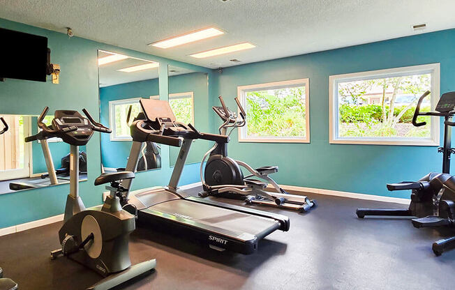 a gym with various exercise equipment and windows