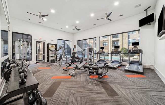A gym with a variety of equipment including treadmills, weights, and exercise machines.