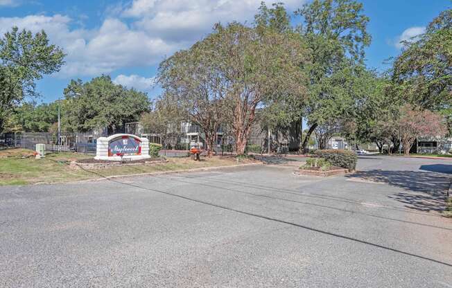 Property signage that says Maplewood with pretty trees and landscaping at Maplewood apartments in Shreveport, LA.