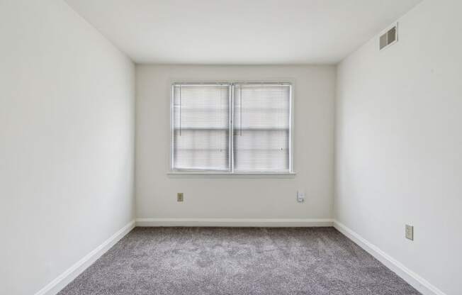 an empty room with white walls and a window