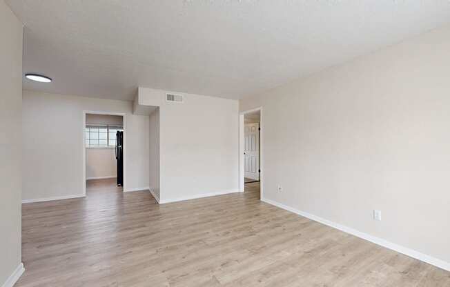 the spacious living room and dining room with hardwood flooring and white walls