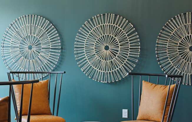 a living room with two orange chairs and two round stools in front of a green wall