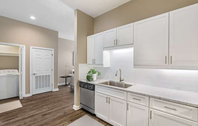 a white kitchen with white cabinets and a stainless steel sink