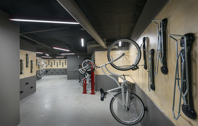 A garage-like room with bikes mounted on the walls and a red repair stand, which includes an air pump and other tools.