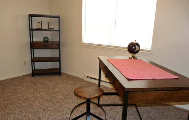 Image of carpeted room with desk and book shelf