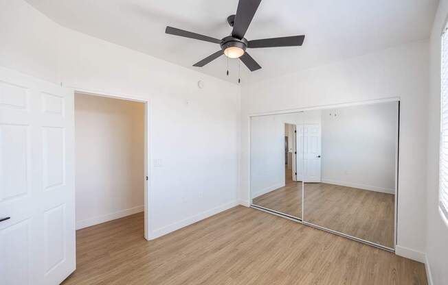 A room with a ceiling fan and a mirror on the wall.