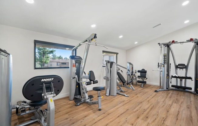 a gym with exercise equipment and weights on a wooden floor