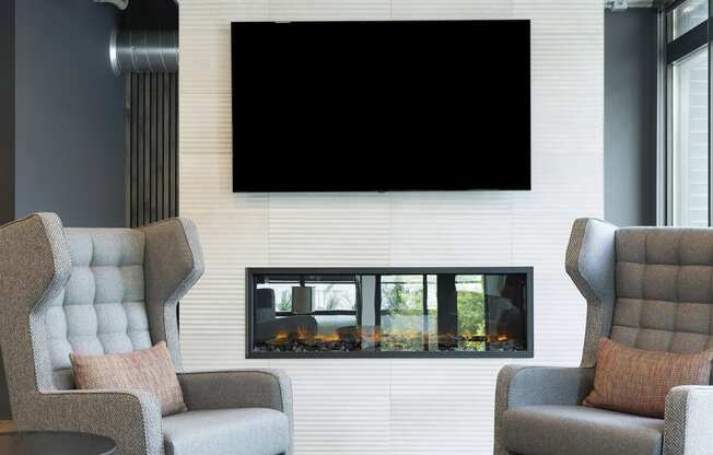 a living room with two chairs and a television on the wall