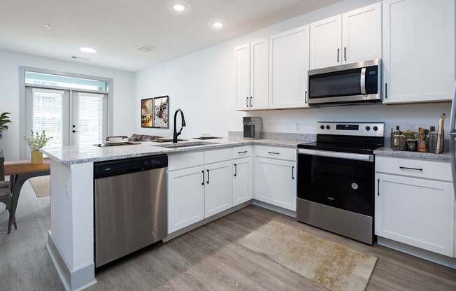 A modern kitchen with white cabinets and stainless steel appliances.