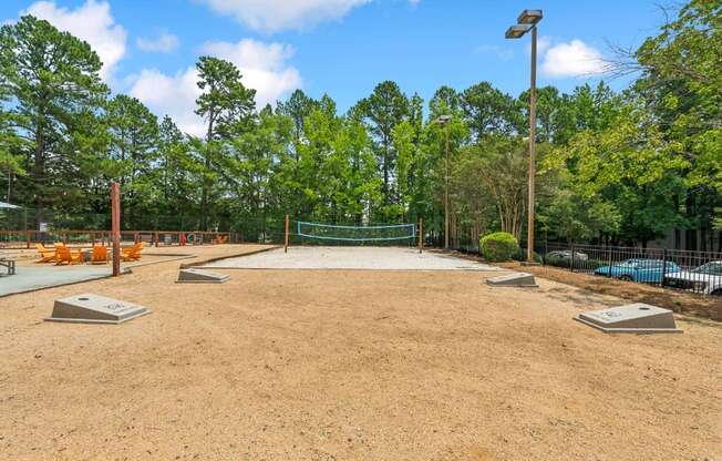 A baseball field is being prepared for a game with a green fence and trees in the background.