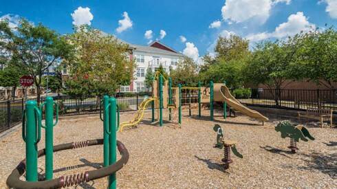 a playground at a park with trees and a building