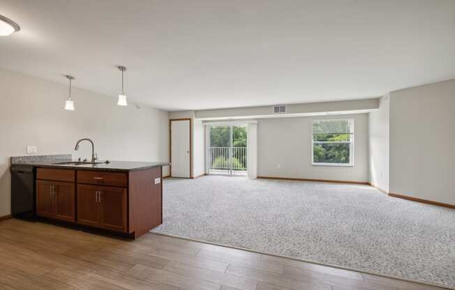 an empty living room and kitchen with wood flooring and a window