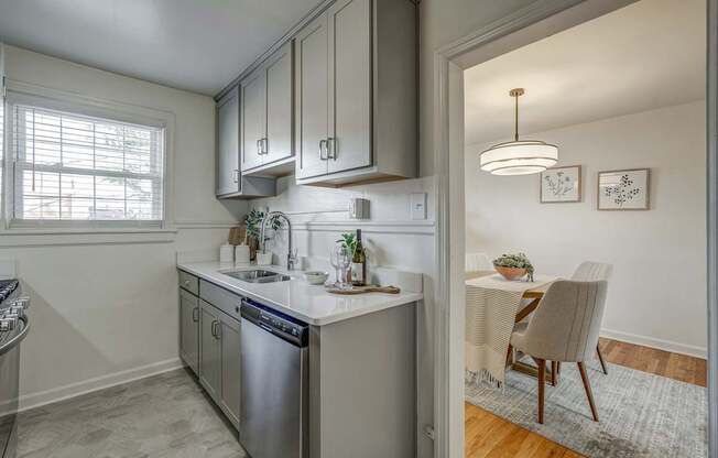 A kitchen with a dining table and chairs in the other room.