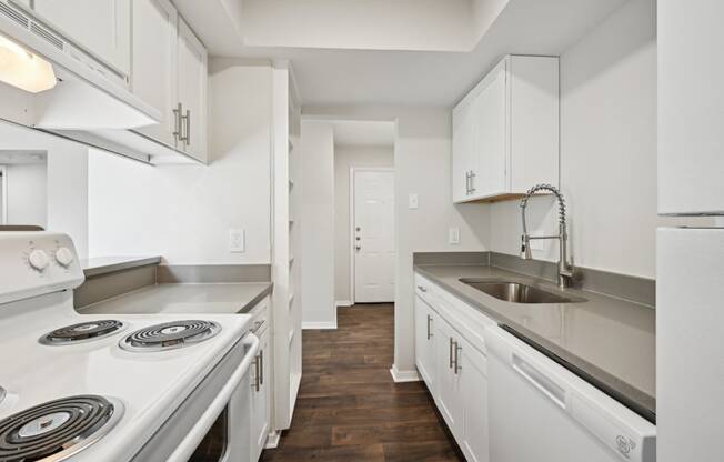 an empty kitchen with white cabinets and appliances and a sink at Woodlands of Plano in Plano, TX