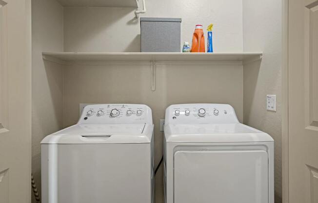 Two white front loading washing machines in a small laundry room.