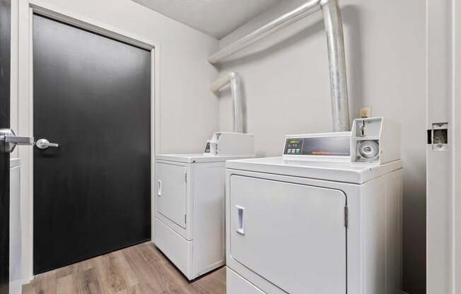 A room with a black door and two white appliances.