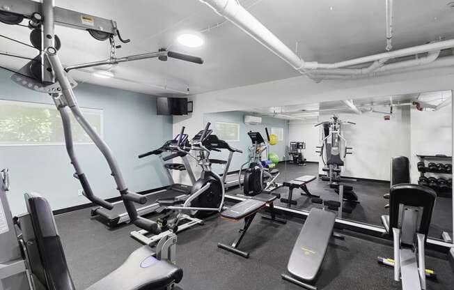 a room filled with lots of different types of exercise equipment for resident use at King Arthurs Court, Seattle, 98125