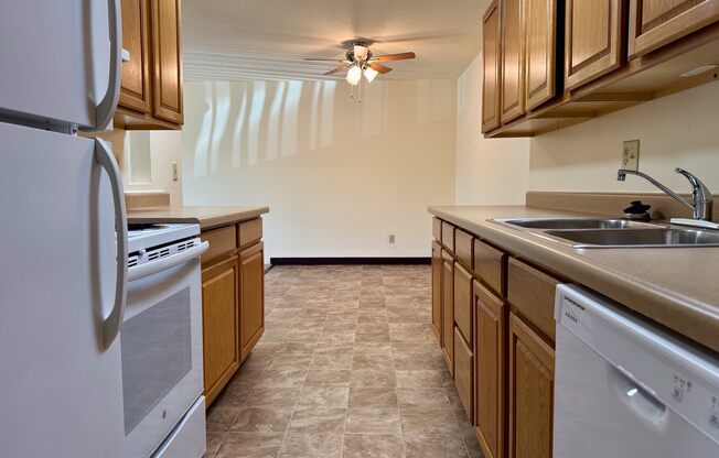 A kitchen with a white refrigerator, a white dishwasher, and wooden cabinets.