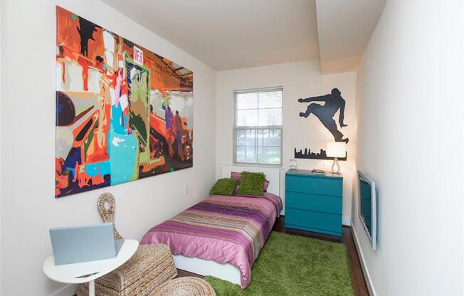 small bedroom with bed, dresser, desk and window at fairway park apartments in washington dc