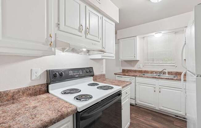 A kitchen with a stove top oven and white cabinets.