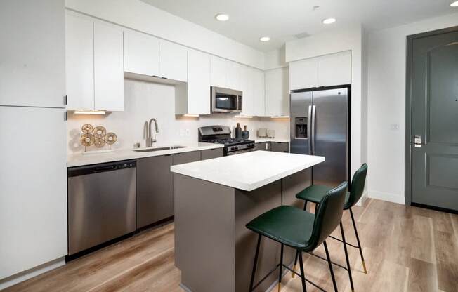 A modern kitchen with a white island and stainless steel appliances.