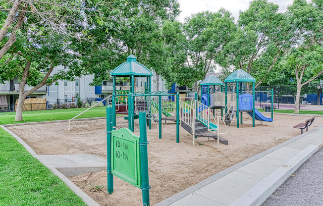 a playground with two swings and a bench in a park