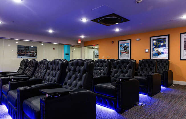 a cinema room with a row of black leather chairs and a projector screen