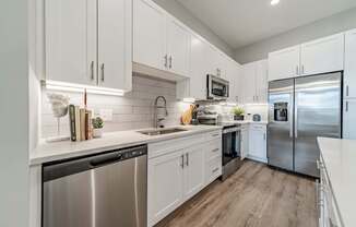 A modern kitchen with white cabinets and stainless steel appliances.