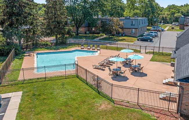 A pool surrounded by a fence and chairs.