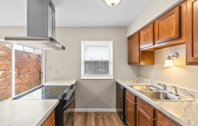 A kitchen with wooden cabinets and a brick wall.