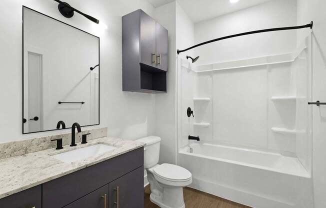A white toilet sits next to a sink in a bathroom.at Boardwalk at Research Park, Huntsville, AL 35806