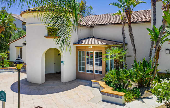 A white house with a brown roof and a brown bench in front of it.