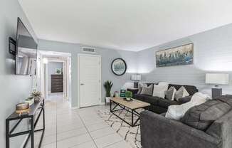 A living room with a grey couch and a painting on the wall.