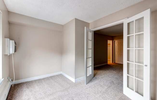 an empty living room with open doors to a hallway