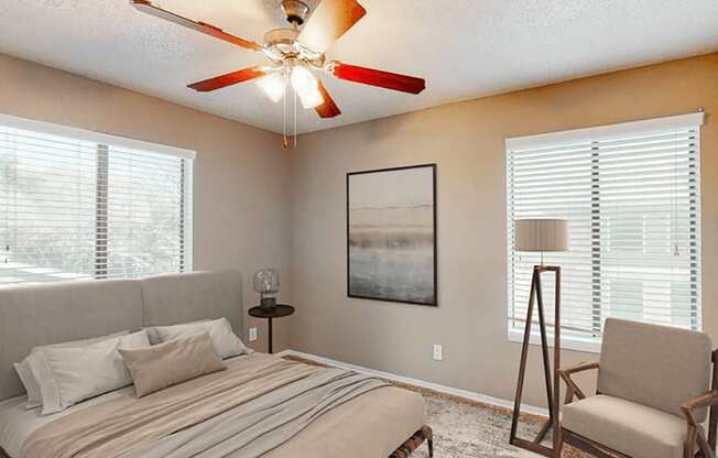 a bedroom with a ceiling fan and two windows