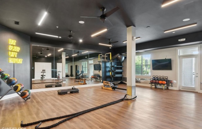 a workout room with weights and mirrors and a large window