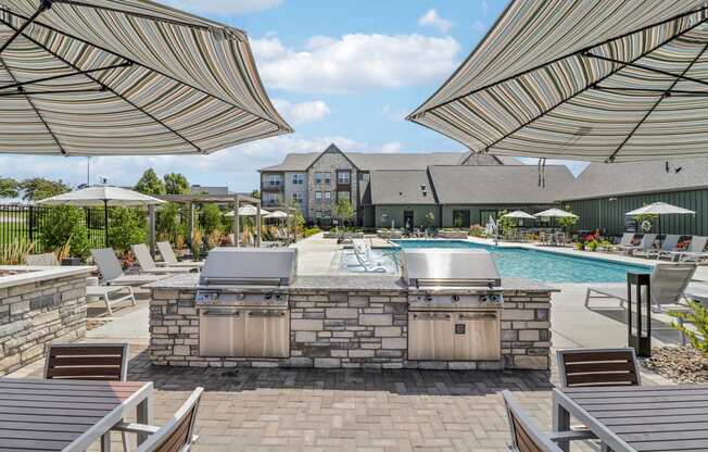 a resort style pool with a grill and umbrellas at The Depot Raymore, MO 64083