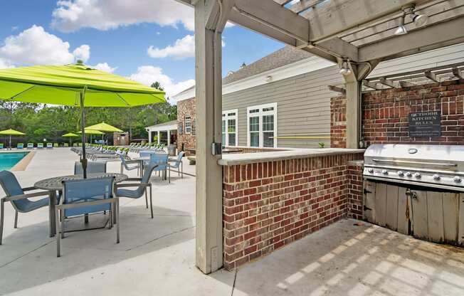 a covered patio with a barbecue grill and tables with umbrellas