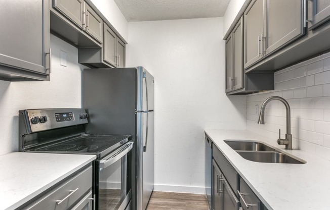 a kitchen with gray cabinets and white countertops