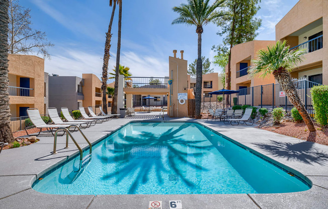 a resort style swimming pool with palm trees and lounge chairs