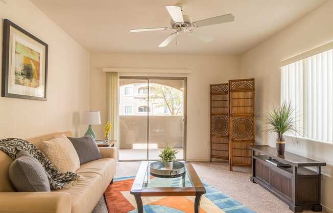 Desert Sands living room with ceiling fan and back sliding door. 