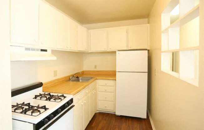 a kitchen with white appliances and white cabinets at Gates of West Bay, Norfolk
